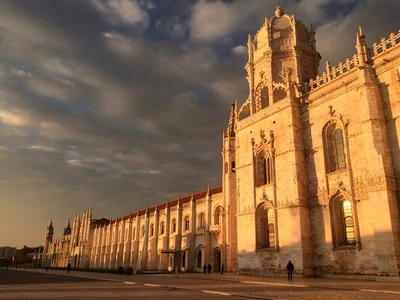 Mosteiro dos Jeronimos in Belem Lisbon at golden hour, late-Gothic Manueline limestone facade with twin pinnacled towers